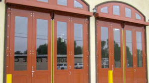 Custom architectural four-fold doors with large glass windows and arched tops